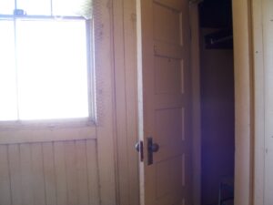 Image of a bleak room with a sunlit window and an open closet door